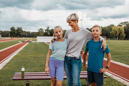 Beautiful blonde athletics mother running coach with her children after a training session on the running track