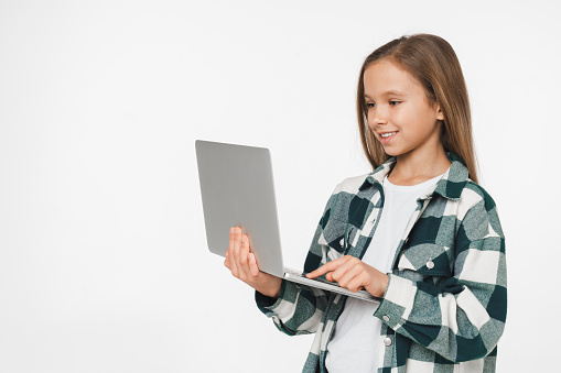 Smart young preteen teenager schoolgirl using online laptop for e-learning e-commerce, distant education isolated in white background