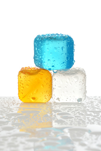 three reusable plastic ice cubes with water on white background