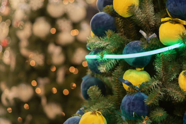original weihnachtsbaum, weiche plüschkugeln blau und gelb mit neongirlande - christmas tree bead humor stock-fotos und bilder