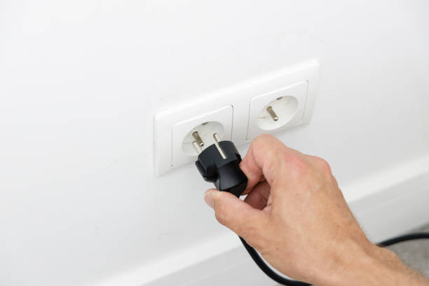 ahorro de energía en casa, quitando el enchufe de la toma de corriente - electric plug outlet pulling electricity fotografías e imágenes de stock
