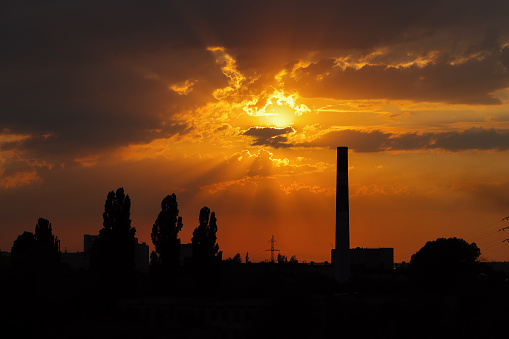 Silhouette of a chimney at sunset, in the rays of the sun