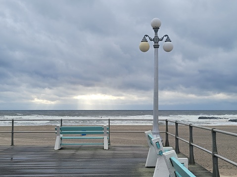 The pier in Avon by the sea. Cloudy ocean. Benches. Lamp post.
