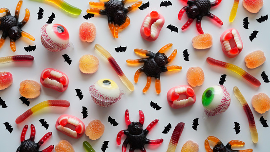 Close-up bright jelly candies,spiders,eyes,jaws,worms and bats,on white background,top view,flat lay,copy space.Decor concept for Halloween party,holiday treat,junk food.Pattern