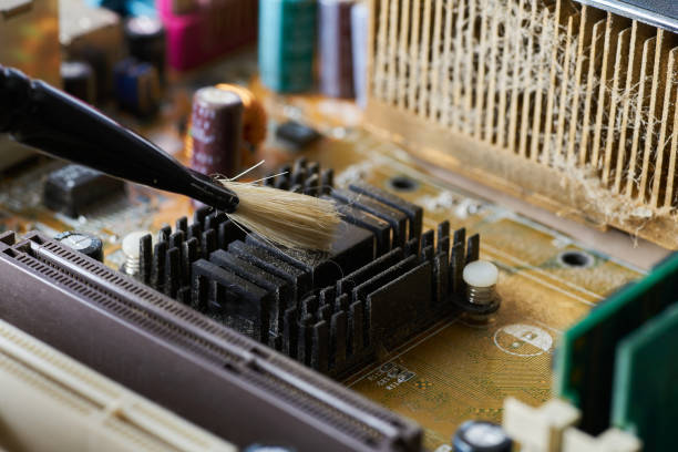 istock Brush cleaning an old computer board from dust and dirt. Close-up. 1422796316