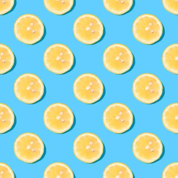 Seamless summer background with lemon slices - absolutely seamless pattern with yellow lemons on a blue background