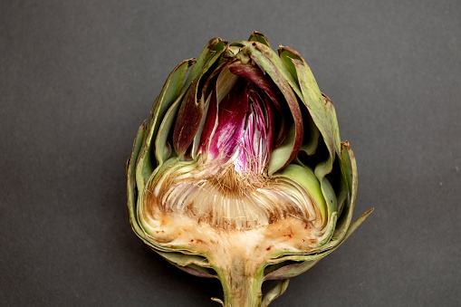 Fresh raw half cut artichokes closeup on black background