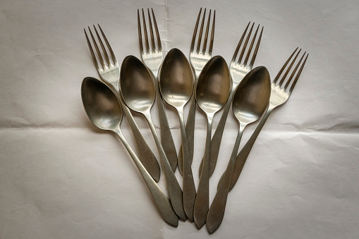 Five forks and five spoons arranged on a white paper tablecloth