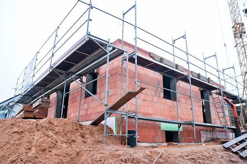 Construction site of a terraced house, the basement and the ground floor of the house are already finished in the shell state.\nThis image is part of a construction site series.