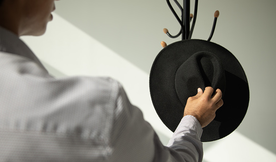 Man hand black hat in hanger.
