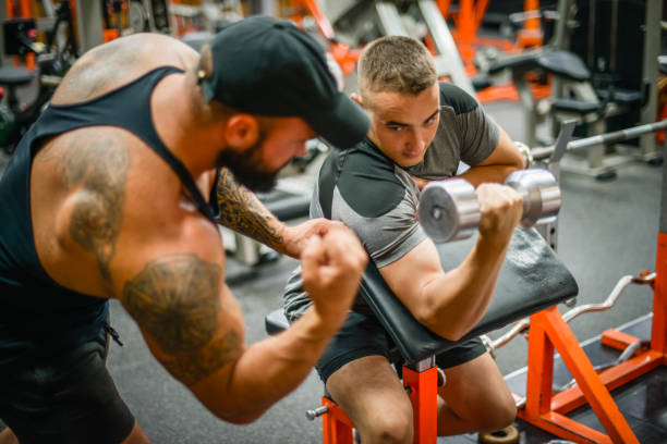 mann, der übungen im fitnessstudio mit einem manntrainer athletischen körperbau macht - abdominal muscle muscular build barbell bicep stock-fotos und bilder
