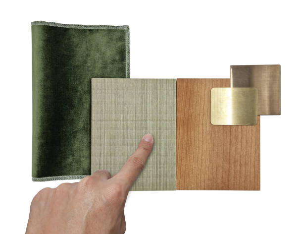 istock interior designer's hand choosing group of interior material including gold brushed stainless, ash and oak wooden veneer, green velvet fabric samples isolated on white background with clipping path. 1422816560