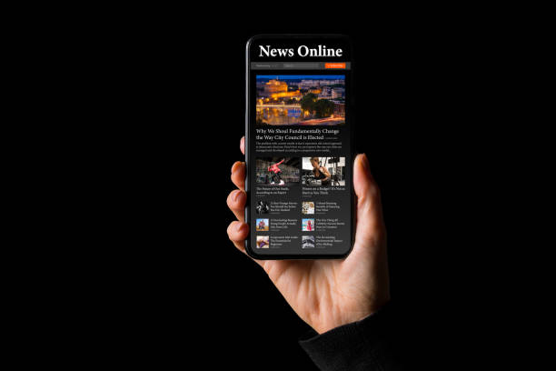 Person holding phone in hand with sample news website on the screen stock photo