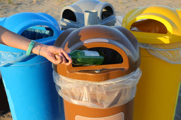 istock waste bin for separate collection on the beaches and a hand that throws away a bottle 1422818353