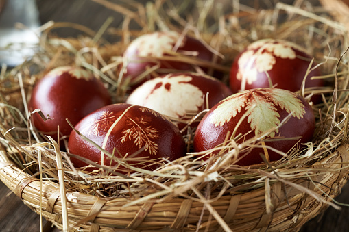 Easter eggs dyed with onion peels with a pattern of herbs in a basket, close up
