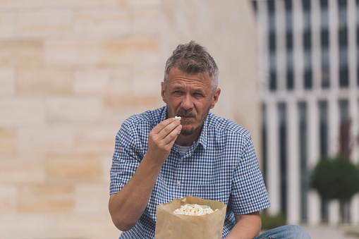 Man is eating popcorn outdoors in the city