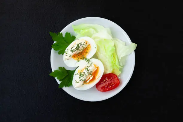 Hard boiled eggs with mayonnaise, lettuce and tomatoes on a plate - top view