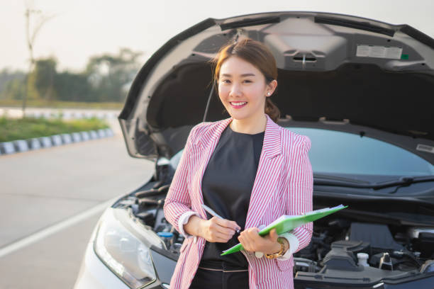 Car Insurance Agent, Young Asian saleswoman writing on clipboard with Broken car , smiling and look at the camera stock photo