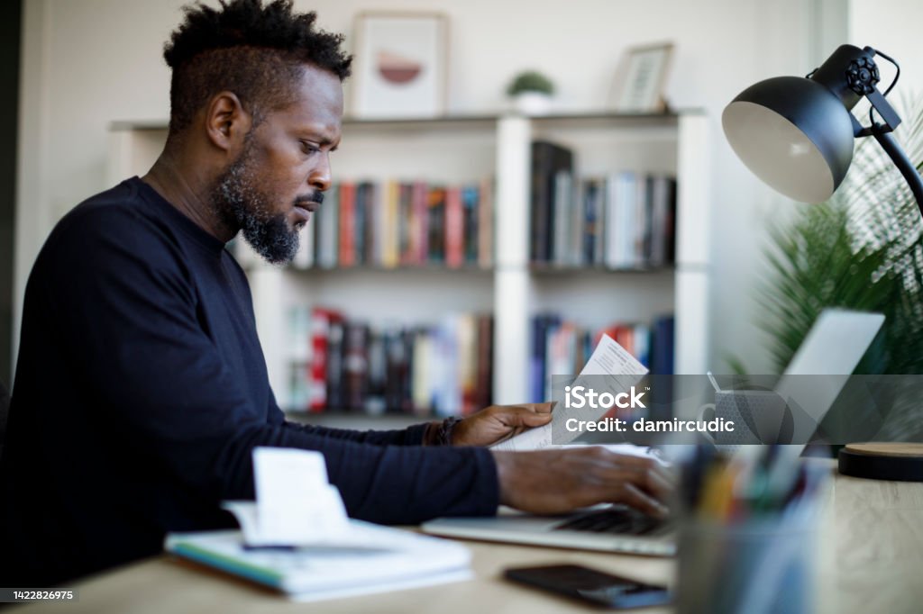Man paying his utility bills online and looking worried Paycheck Stock Photo