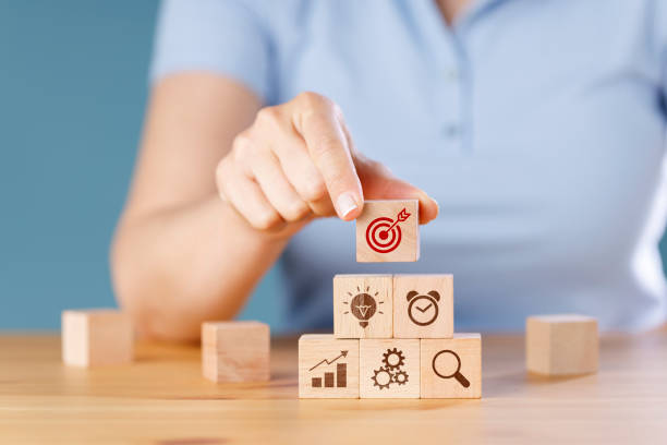 istock Female hand putting wooden cube block stacking with icon on blue background. Concept of business strategy and action plan 1422832422