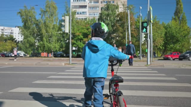 Boy crossing the road with bicycle in the evening. Boy on crosswalk. 4k video footage UHD 3840x2160