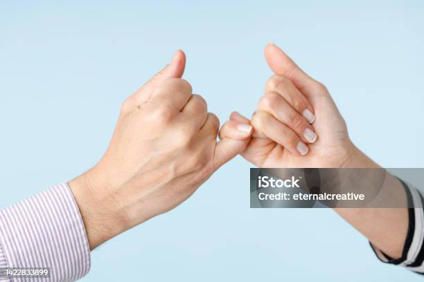 Two People Making A Bet In Front Of A Blue Background Stock Photo - Download Image Now