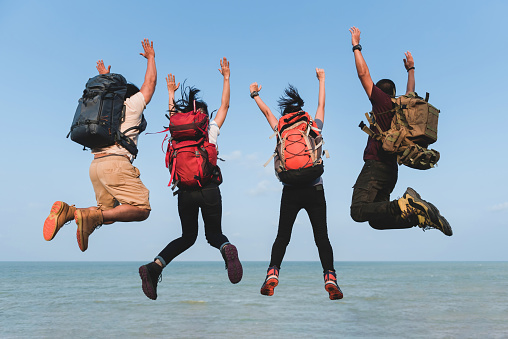 Male and female, Asian, backpacker Hiking and climbing four people , jumping together floating in the air, at sea.