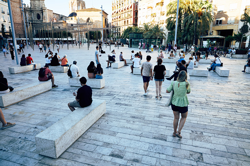 Main square, recently renovated and redesigned, in Valencia, Spain with people sitting on the different concrete benches.
