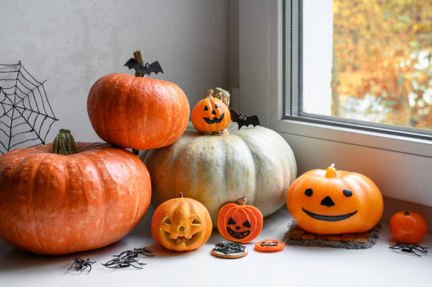 istock Halloween still life by window at home. Pumpkins, sweets and decorations on white windowsill 1422841041