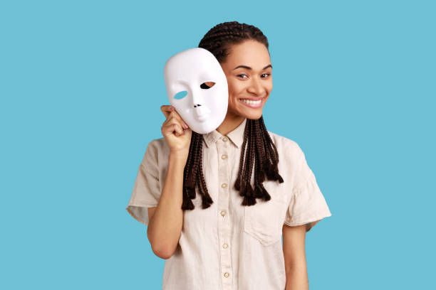 istock Woman removing white mask from face showing his smiling expression, pretending to be another person. 1422843556