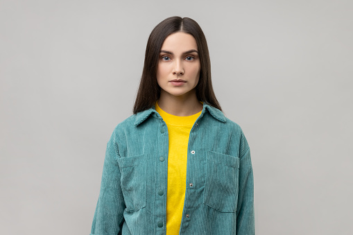 Portrait of strict bossy woman looking at camera, feels confident focused self-assured, expressing seriousness, wearing casual style jacket. Indoor studio shot isolated on gray background.