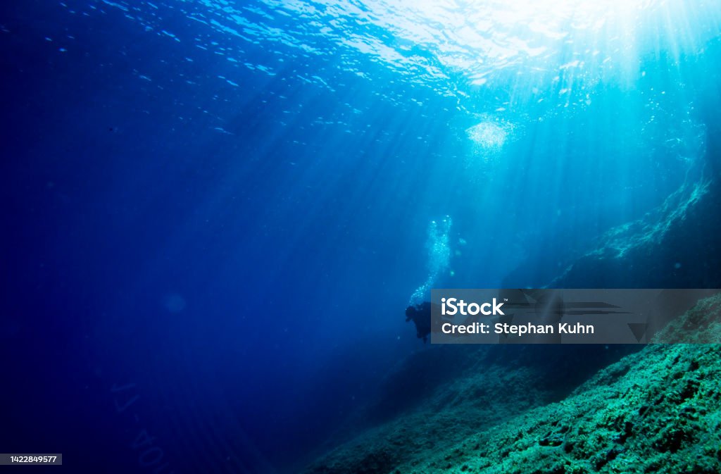 Sun rays underwater Komiza, Vis Island, Croatia on September 6, 2017: diver enjoys sun rays breaking through the water surface at the adriatic coast Adventure Stock Photo