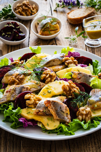istock Marinated herring fillet with beetroots, apple, walnuts and greens on wooden black table 1422850091