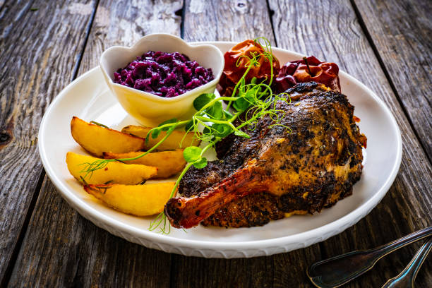 muslo de pato asado y verduras servidas en mesa de madera - animal leg duck meat chicken leg herb fotografías e imágenes de stock