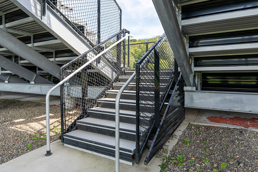 Example of an exit, entrance, vomitorium at empty set of metal stadium bleacher - grandstands with steps and railing. Nondescript location with no people in image. Not a ticketed event.