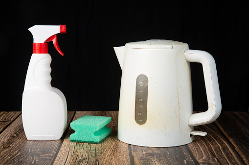 Cleaning a plastic white kettle with special chemicals.House cleaning.