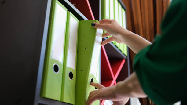 istock Female hands takes folder with documents from shelf in archive 1422854340
