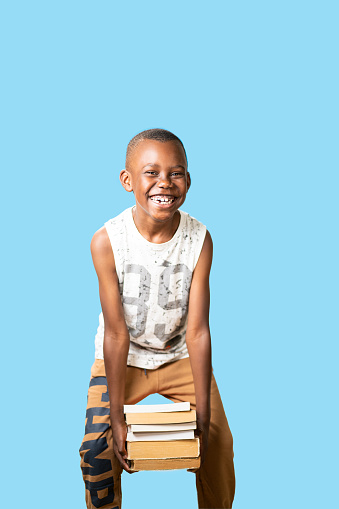 retrato con fondo azul de un joven estudiante sostiene todos los libros con felicidad photo