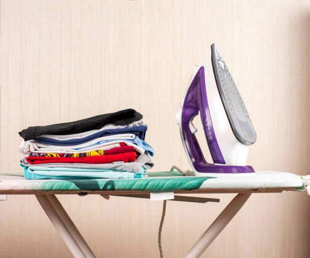 istock a stack of ironed laundry on the ironing board next to the iron 1422858433