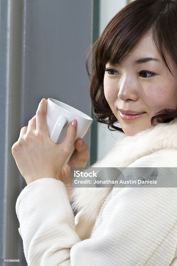 Азиатская девочка, пить кофе в окно перед большой - Стоковые фото 20-24 года роялти-фри