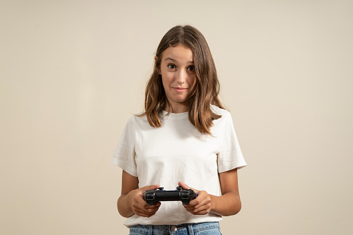Portrait of cute active and energetic teenage girl having vacation using video game console feeling satisfied wearing t-shirt isolated on colorful background