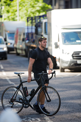London, UK - June 22, 2022: Young man cycling at work by bike and make a spot by the traffic lights. People cycling into the City of London
