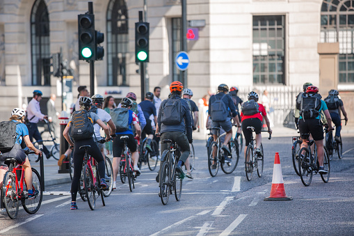London, UK - June 22, 2022: People cycling at work by bike and make a spot by the traffic lights. People cycling into the City of London