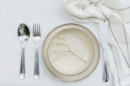 Place setting in white - plates, cutlery in gold, napkin