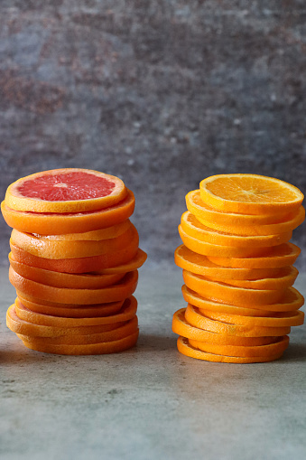 Stock photo showing close-up view of two stacks of citrus fruit slices against a mottled grey background.