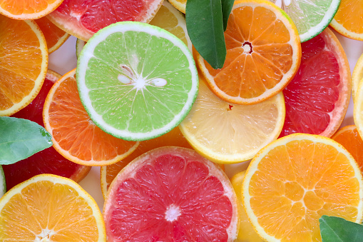 Vibrant juicy citrus fruits on a white marble texture with copy space. Grapefruit, lime, lemon, and orange slices