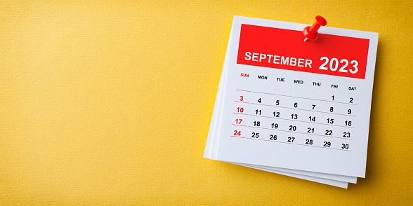 White Sticky Note With 2023 September Calendar And Red Push Pin On Blue Background