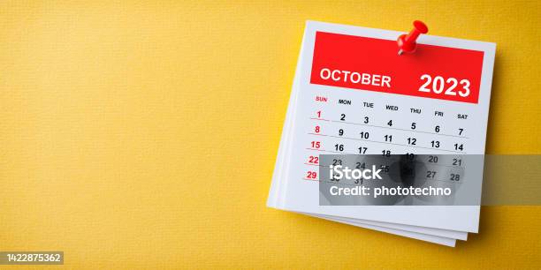 White Sticky Note With 2023 October Calendar And Red Push Pin On Blue Background Stock Photo - Download Image Now