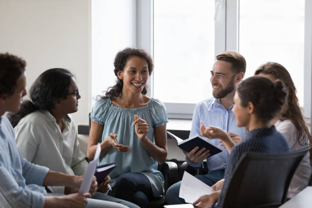 Happy diverse addicts sitting on chairs in circle, talking stock photo