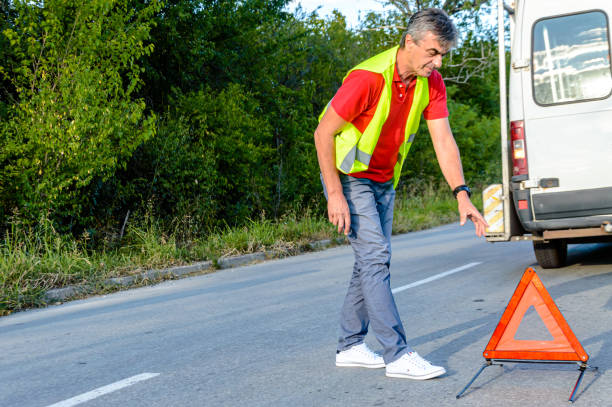 un homme a eu un accident de voiture et met un panneau d’avertissement triangulaire. - reflector danger warning triangle vehicle breakdown photos et images de collection